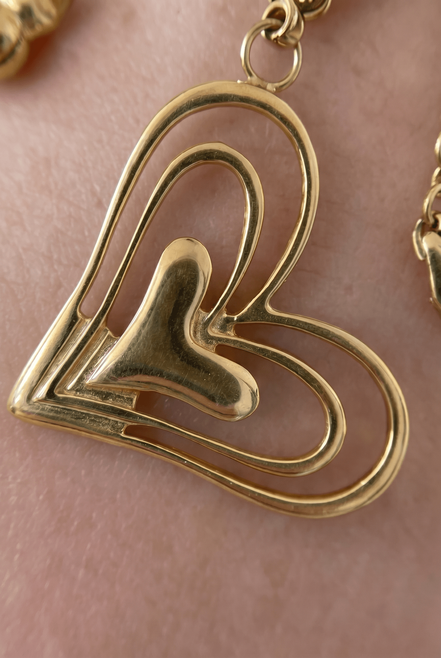 Gold Gilded Heart Charm Bracelet with layered, cutout heart design resting on skin.
