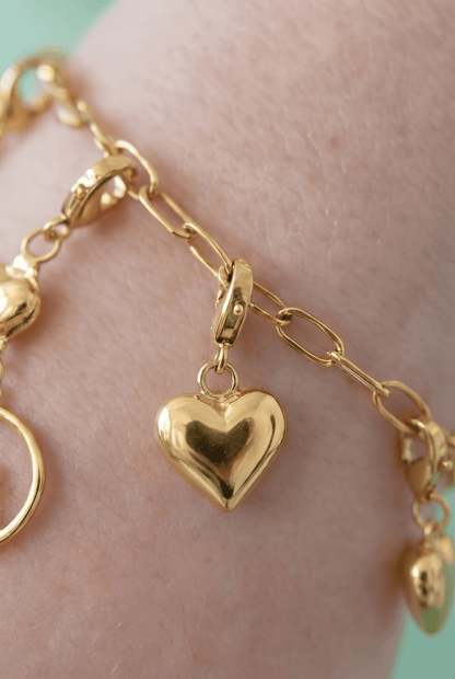 Gilded heart charm bracelet featuring polished gold-tone puffy heart charms on an oval-link chain.