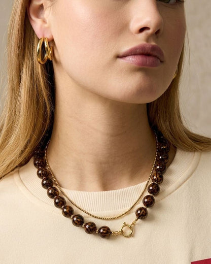 Close-up of a petite leopard acrylic beaded necklace with gold toggle on a delicate model, highlighting bold leopard print and retro style.