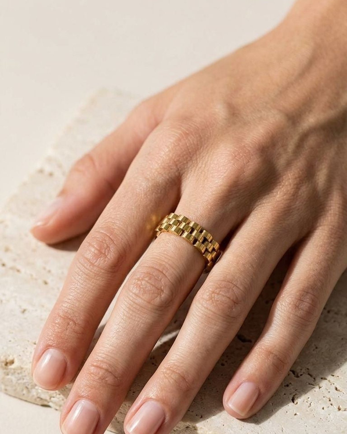 Close-up of Liquid Wavy Drip stainless steel ring on a stone surface, highlighting its irregular wavy shape and polished texture with natural sunlight.