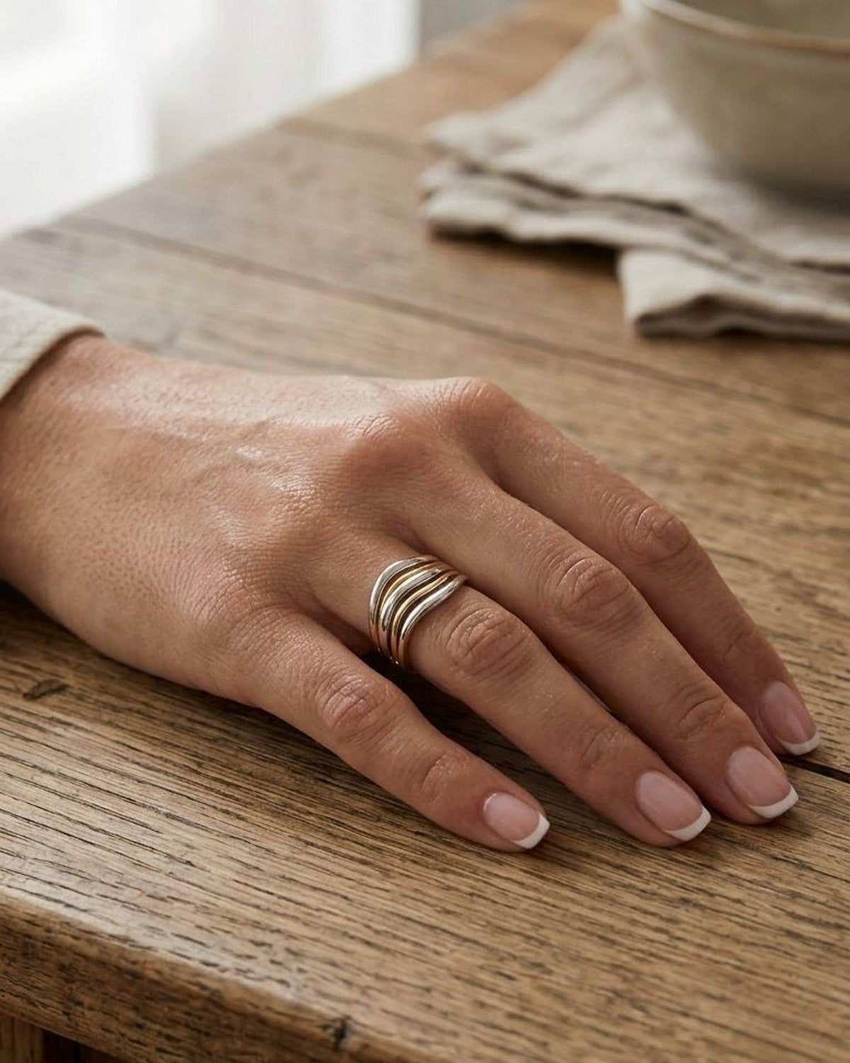 Close-up of the small Liquid Wavy Layer statement ring with interconnected wavy layers on a textured wooden surface, highlighting its minimalist elegance and liquid-like design.
