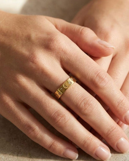 Close-up of Little Stargazer Gold ring on a woman's finger, showing sun pattern and rhinestone accents with soft lighting.