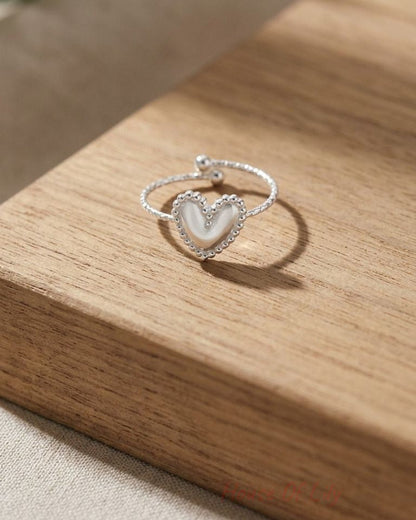 Close-up of the small stainless steel 'Main Character Energy' ring on a wooden surface, highlighting its minimalist design and subtle shimmer.