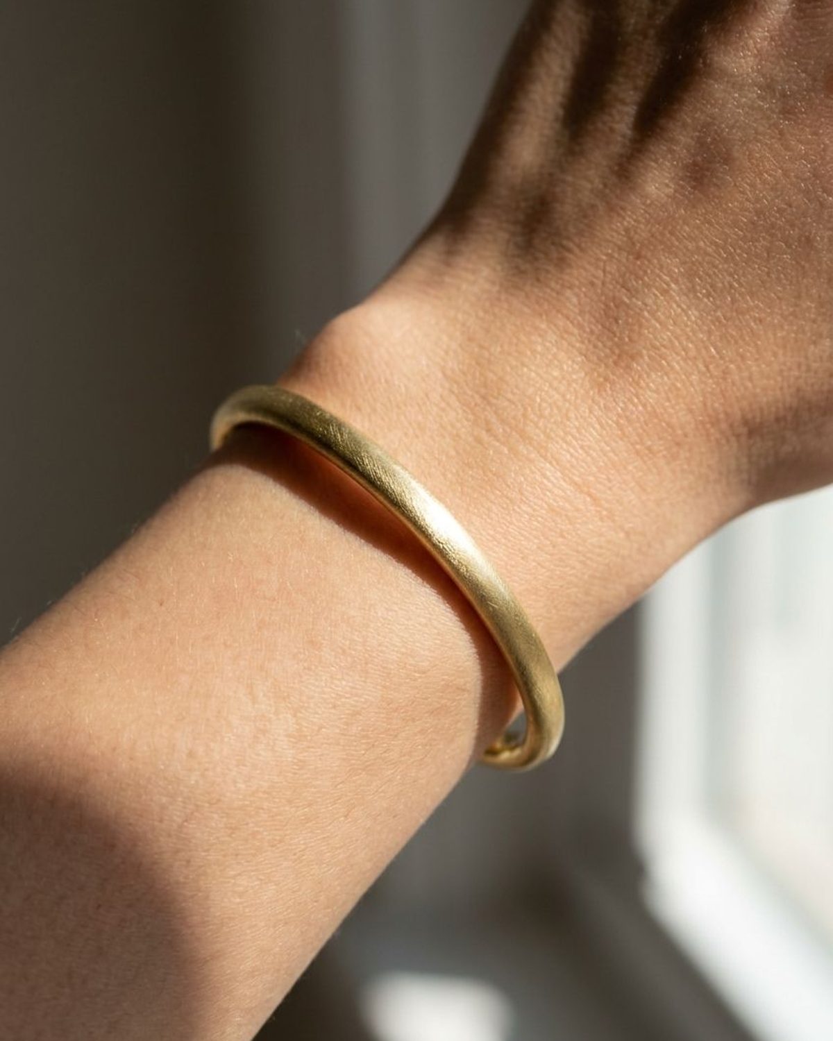 Minimalist brushed stainless steel bangle worn on a female wrist, showcasing a delicate and sleek everyday design.