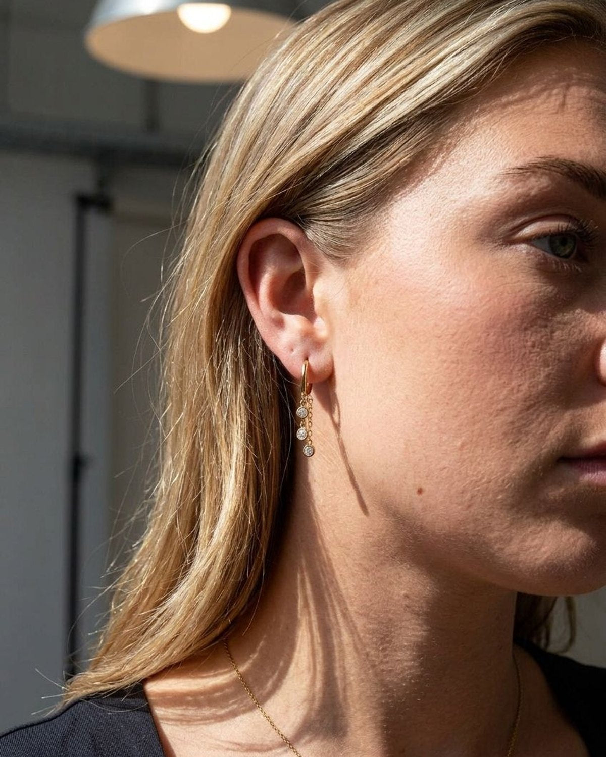 Close up of a model wearing a subtle circle drop earring, highlighting the delicate chain and zircon setting.