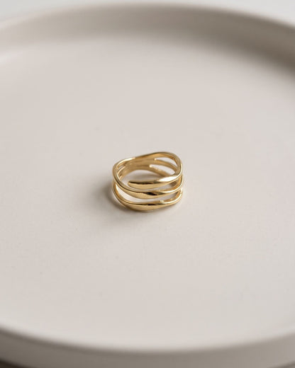 Delicate wave stack ring displayed on a clean matte ceramic surface with soft even lighting.