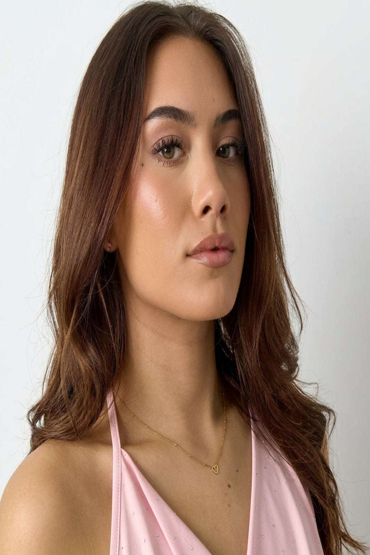 Small open heart pendant necklace in gold color worn by a woman, emphasizing its delicate and minimalist design.