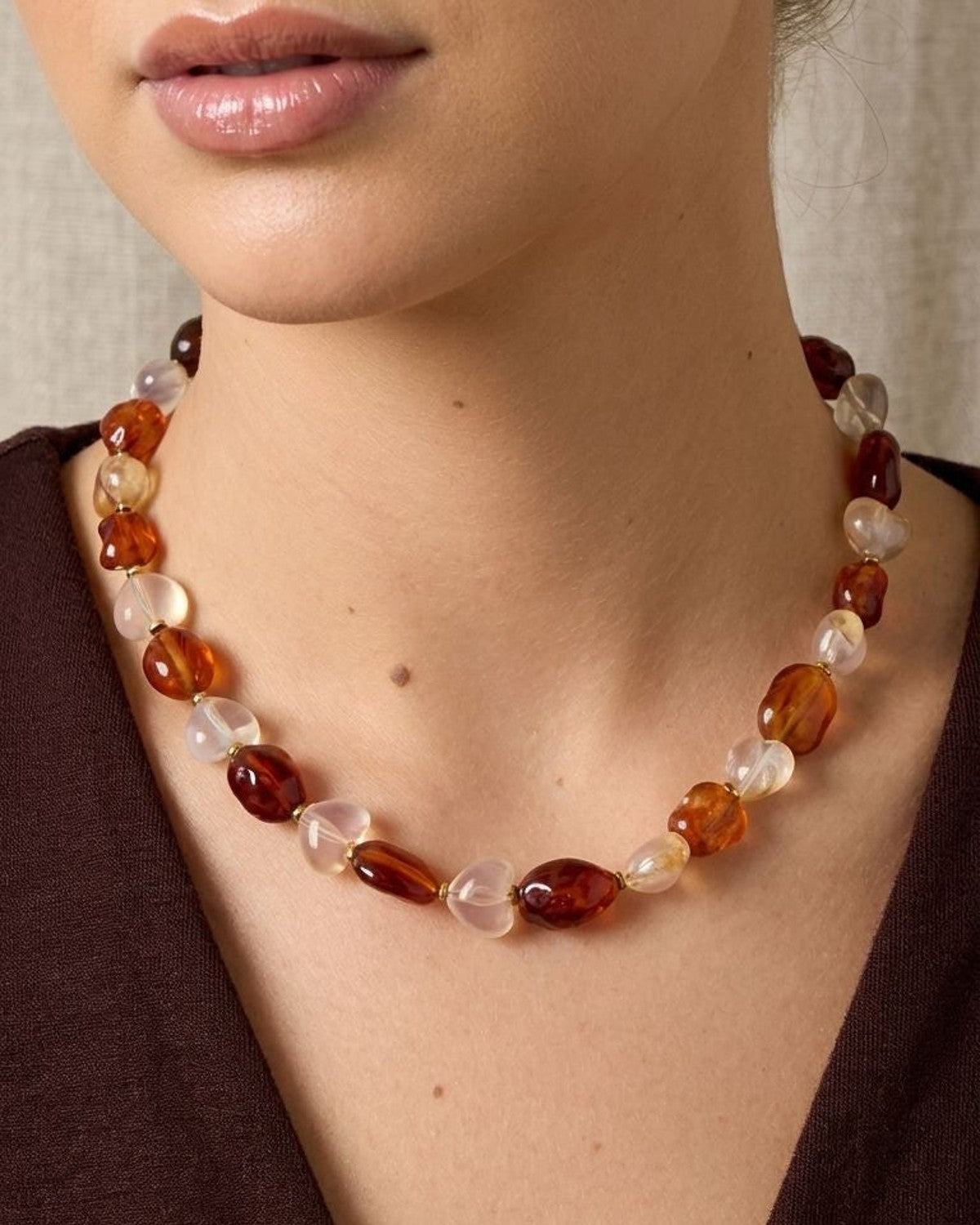 Close-up of Mixed Heart Pebble necklace on a model showing translucent pink, burgundy, amber, and white beads with gold extender clasp.