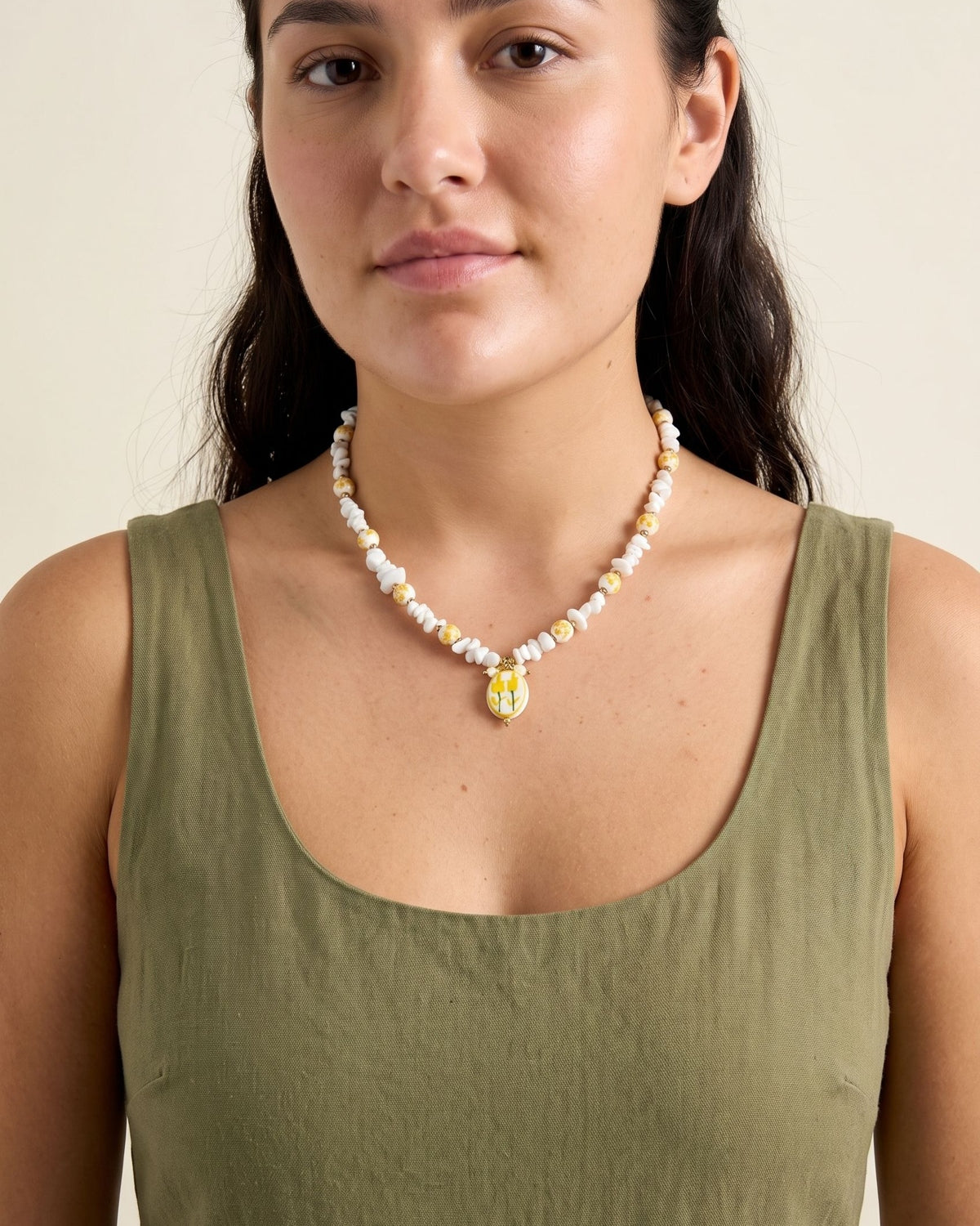 Delicate yellow floral beaded necklace worn by a model to highlight its petite statement design for summer vacation.