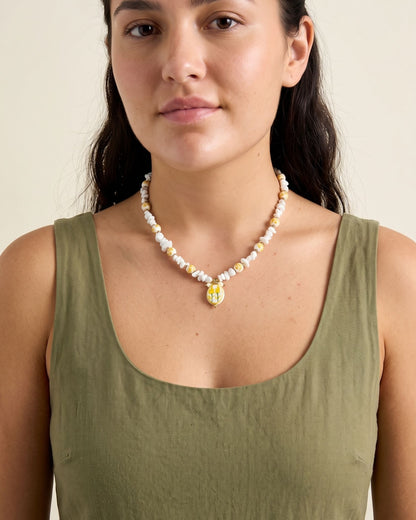 Delicate yellow floral beaded necklace worn by a model to highlight its petite statement design for summer vacation.