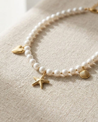 Close-up of the 'Pearl Sea Day' necklace with imitation pearls and sea-themed charms on textured fabric, showcasing its delicate shimmer and coastal style.
