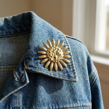 Delicate petal-shaped pin on denim jacket lapel, stainless steel finish, softly lit by natural daylight highlighting intricate details.