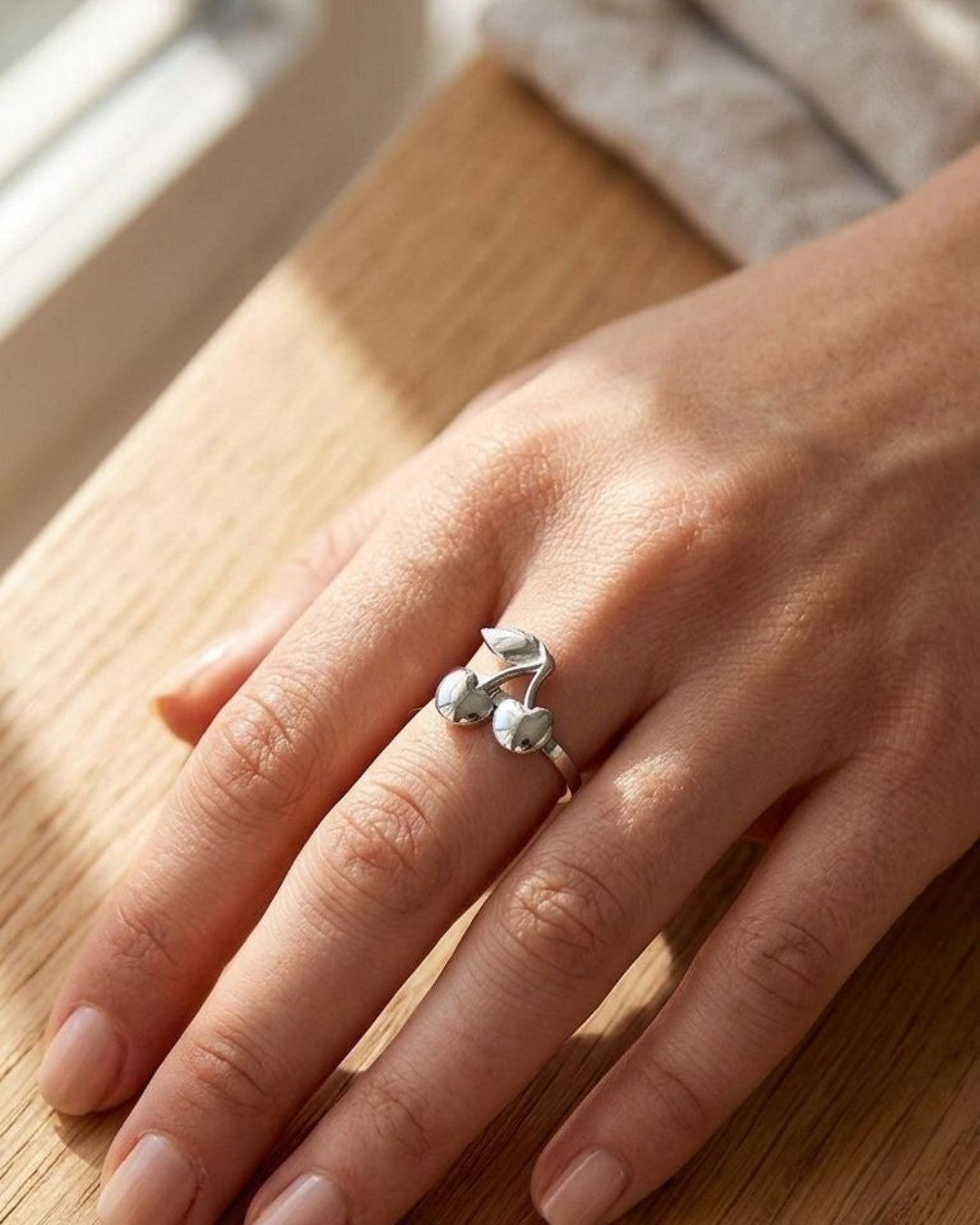 Close-up of the Cherry Pop Statement ring on a model's finger, showcasing glossy cherry motifs on stainless steel with natural sunlight.