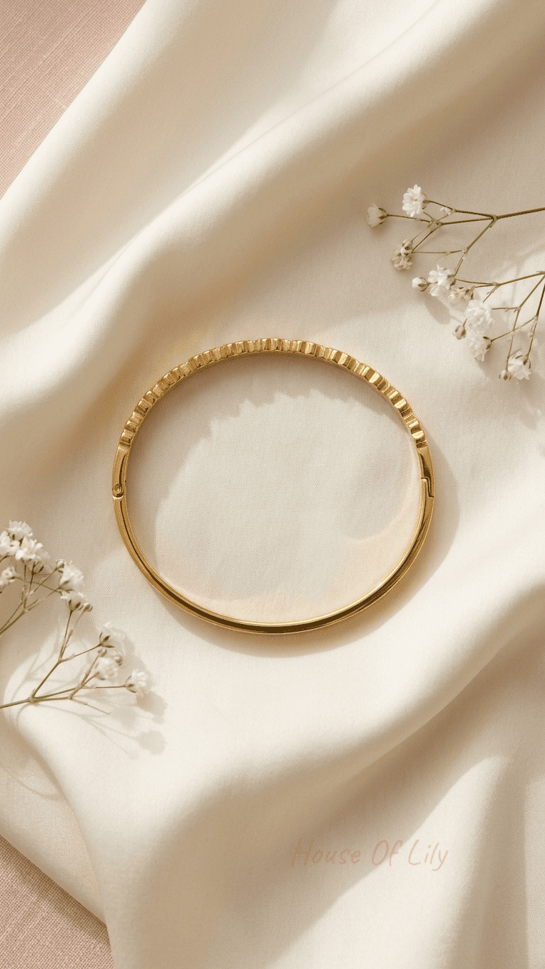 Gold Clover Charm Bangle with a polished finish, resting on cream silk fabric decorated with small white flowers.