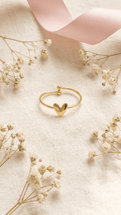 Minimalist gold ring with an open band design, featuring a central heart motif and small bead terminals.
