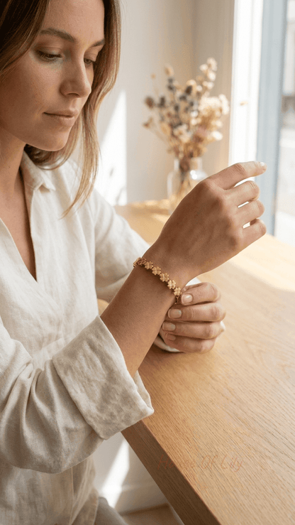Woman wearing a gold bangle bracelet featuring a series of delicate, matte-finish four-leaf clover charms.
