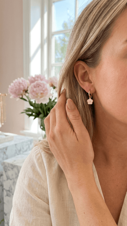 Soft Enamel Bloom Hoops featuring a small, pale pink flower charm hanging from a delicate gold hoop earring.