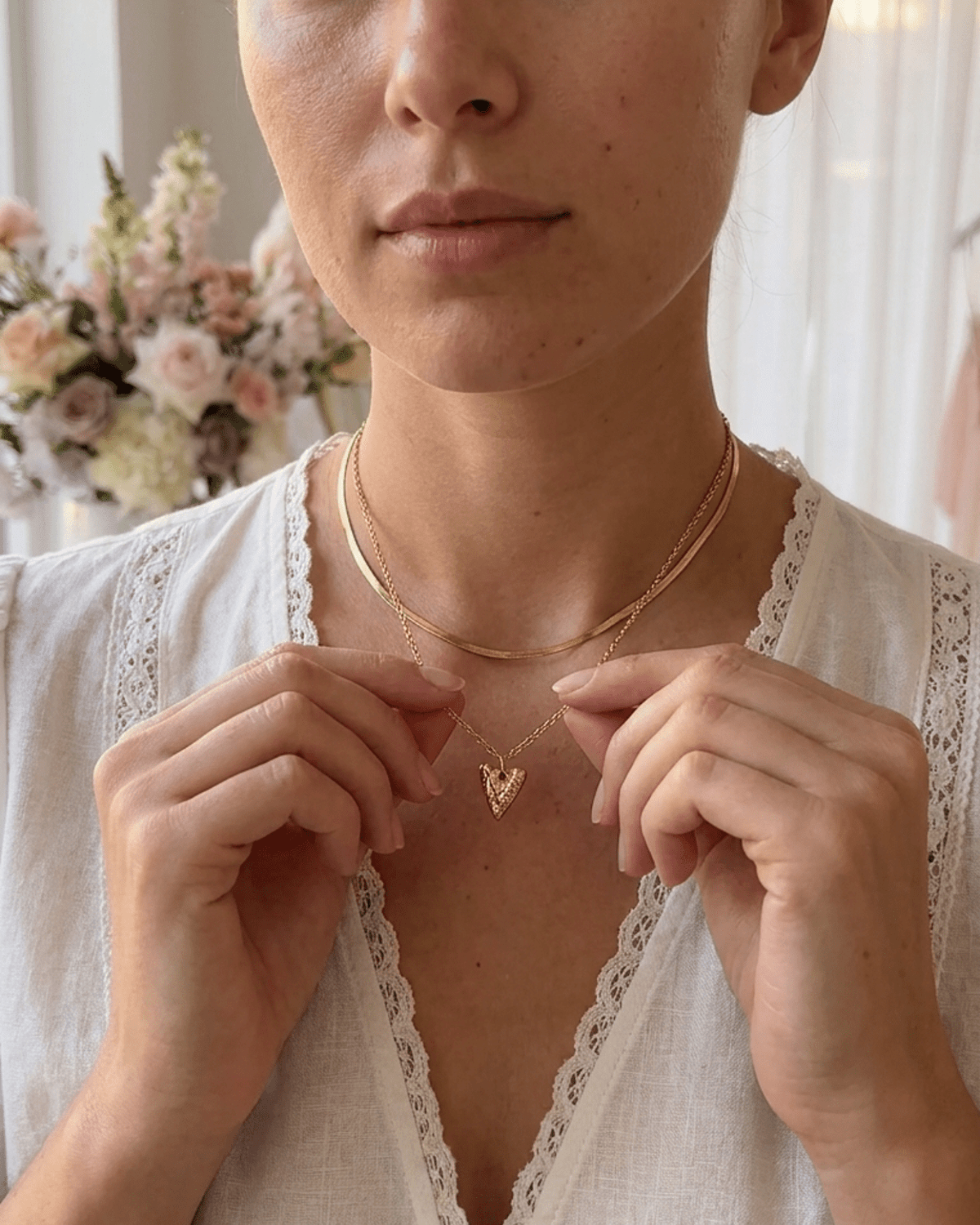 A person wearing the gold-toned Heart Layered Necklace, featuring a flat herringbone chain and a textured heart pendant.