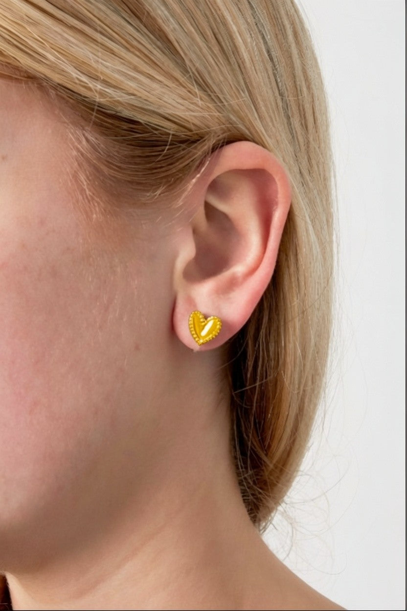 Cutie Heart Clips: Small, shiny gold-tone heart-shaped stud earrings with a delicate beaded edge on an earlobe.