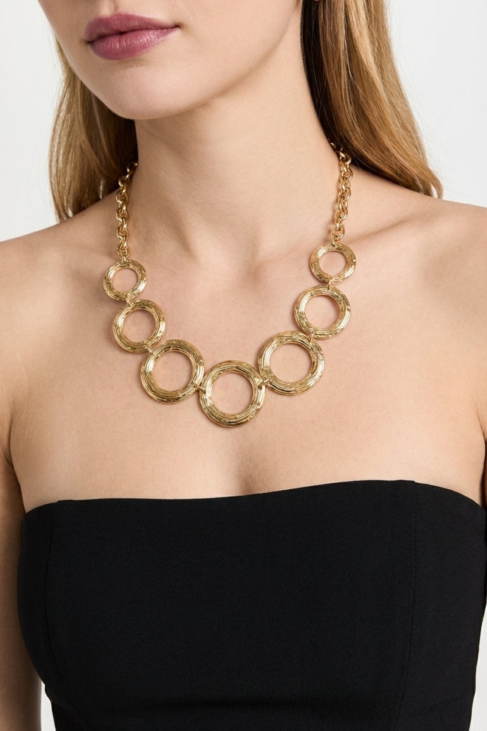Gilded Chain Statement Necklace featuring linked gold-toned textured metal rings forming a bold centerpiece.