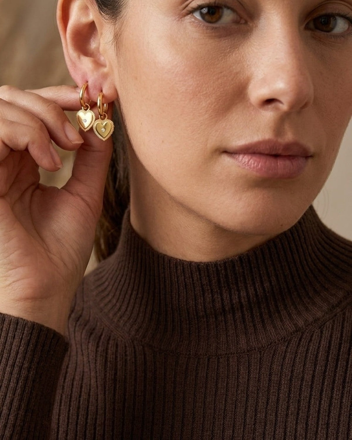 Gold hoop drop earrings featuring puffed heart charms with beaded borders and small center crystals worn on ears.