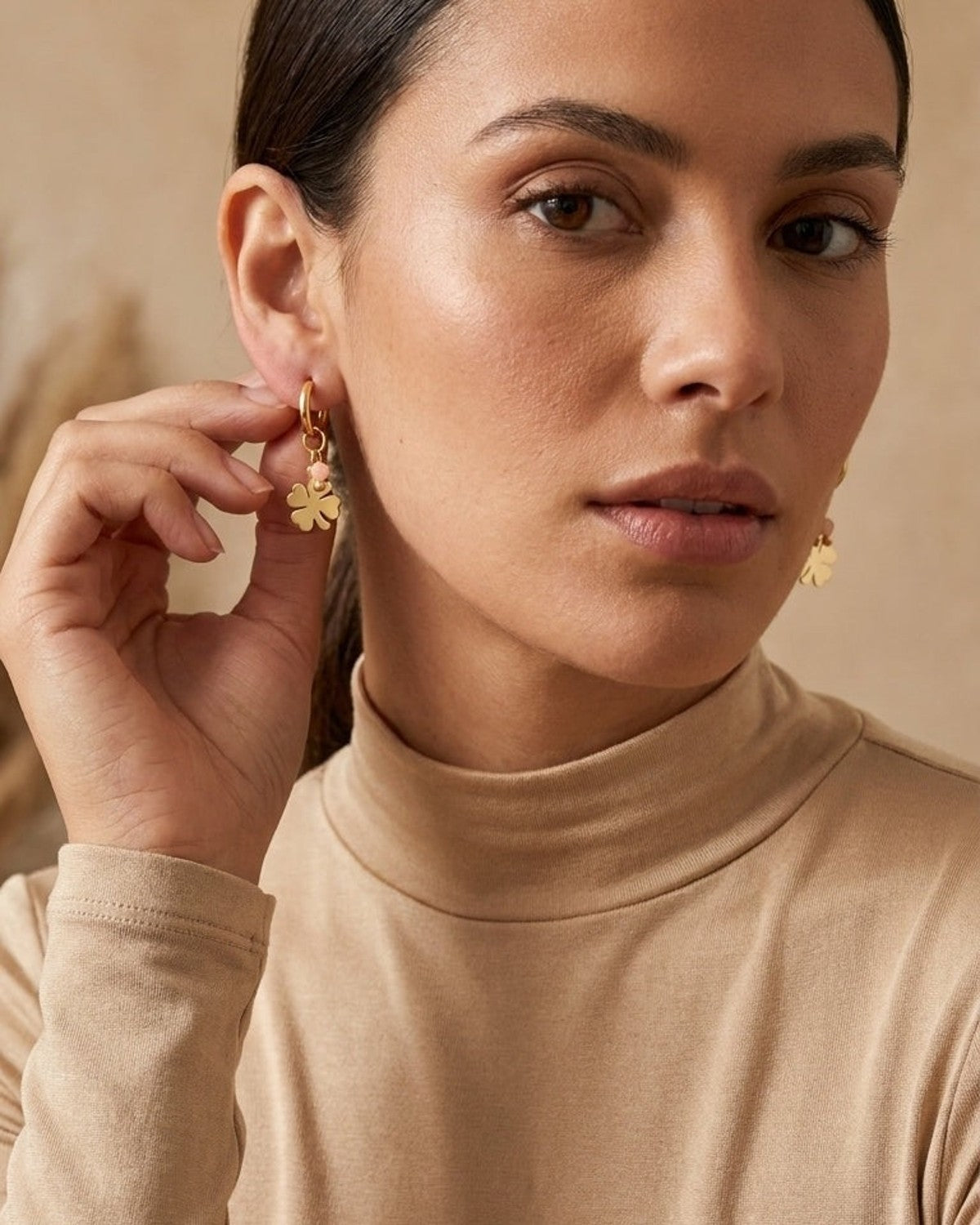 A woman wears House Of Lily's Lucky Girlie Drop gold earrings, featuring a small hoop and clover charm.