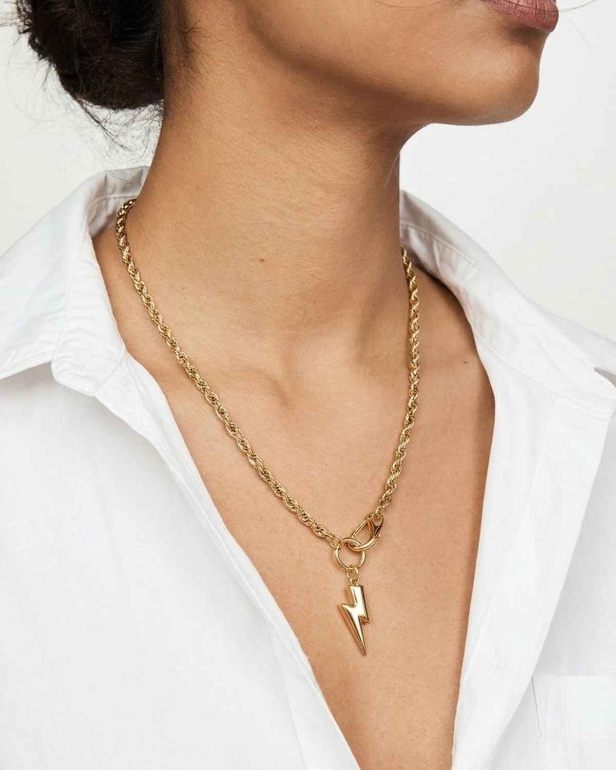 Gold tone rope chain necklace with a lightning bolt pendant.
