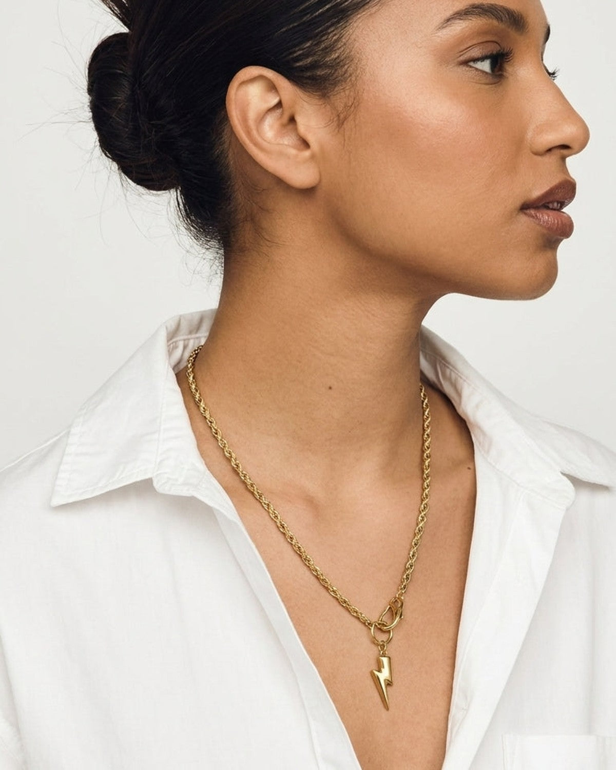 Gold Tone Pendant Necklace with a twisted rope chain and a lightning bolt charm worn on a model.