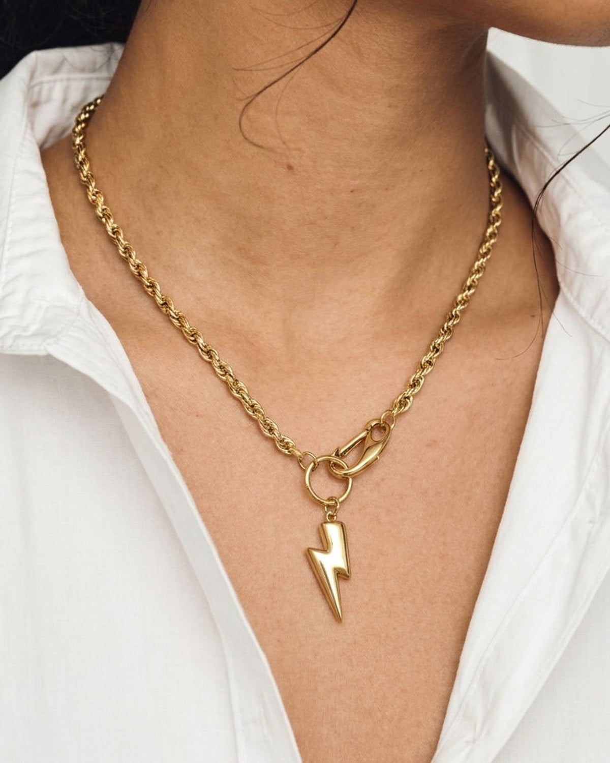 Gold tone rope chain necklace with a polished lightning bolt pendant on a clasp.