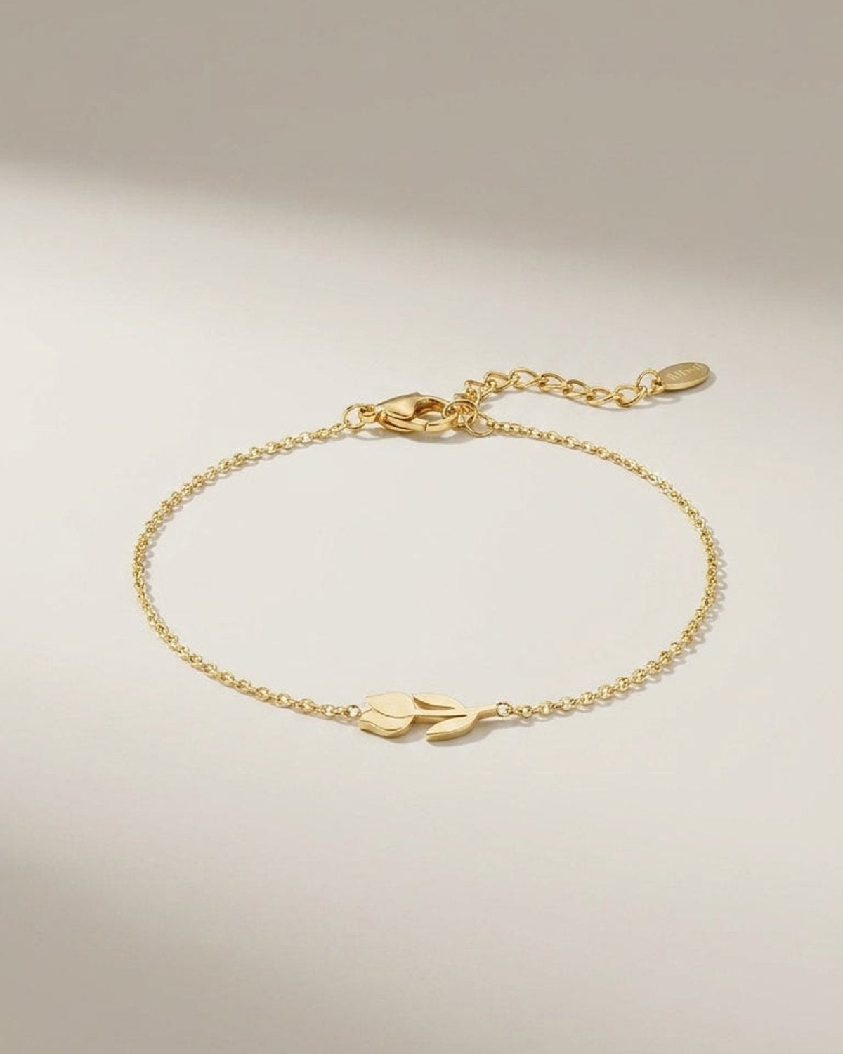 Gold-colored metal chain bracelet featuring a horizontal tulip charm at the center and a lobster clasp closure.