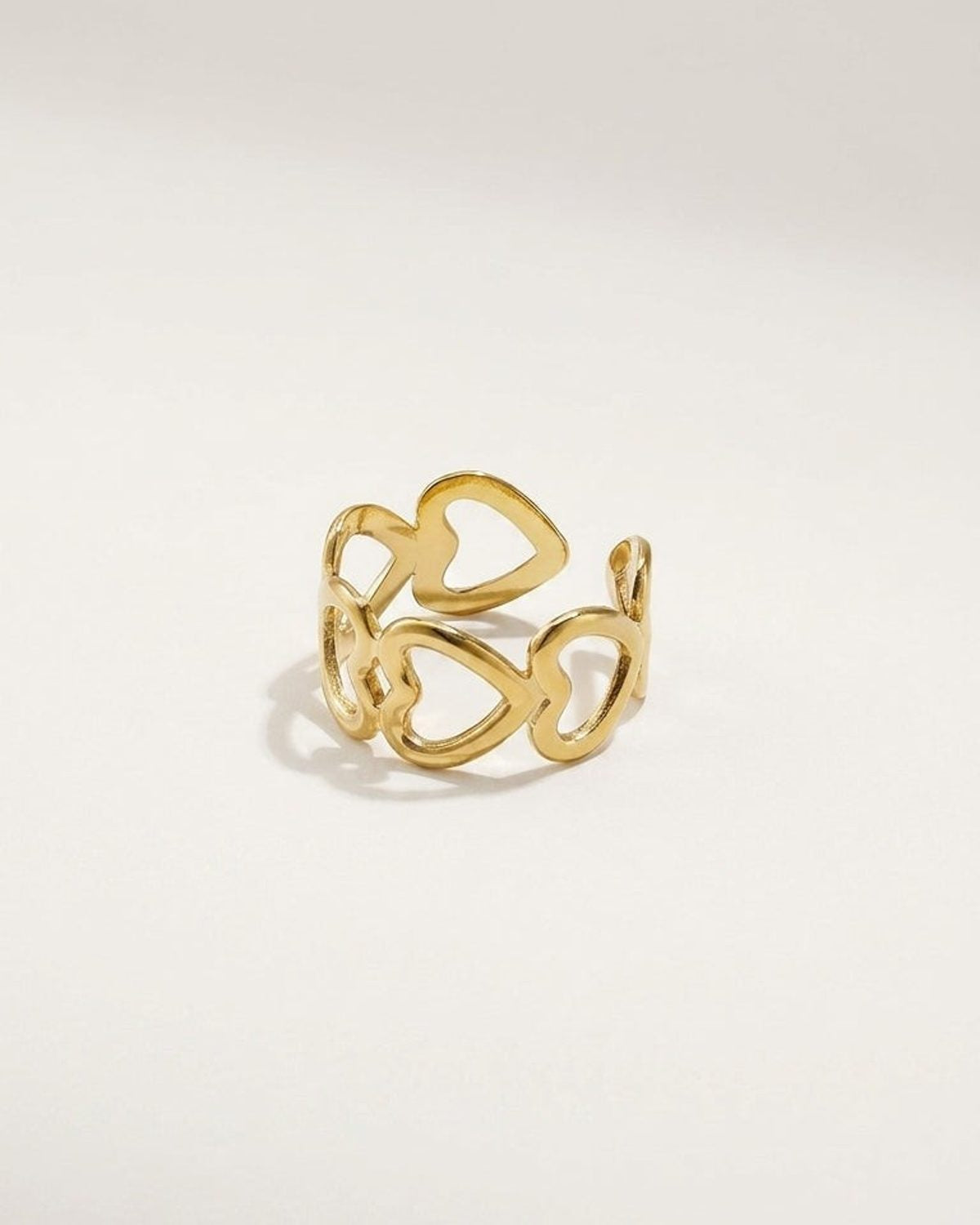 Gold-toned metal ring featuring an open-work band of interconnected cutout hearts.
