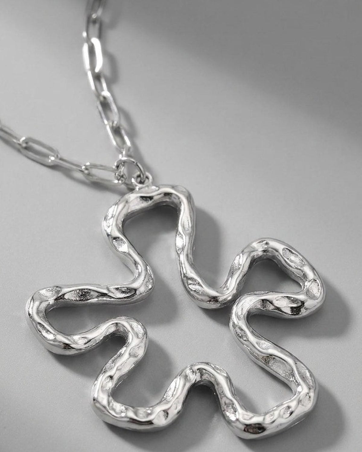 Iconic Lily Flower silver necklace with a textured, abstract floral pendant on a chunky link chain.