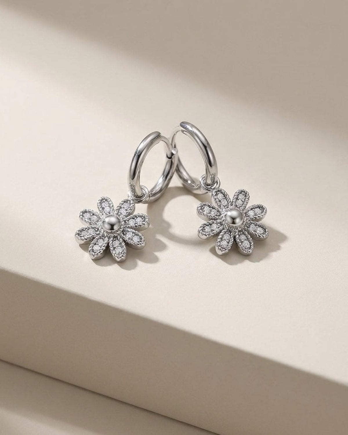 Silver hoop earrings with pavé-set crystal flower drops featuring smooth domed centers.