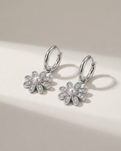 Silver hoop earrings with pavé-set flower charms featuring white pearl centers.