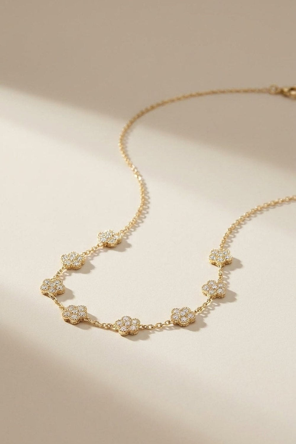 Gold chain necklace featuring multiple pavé zircon-set floral charms along the front.