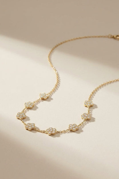 Gold chain necklace featuring multiple pavé zircon-set floral charms along the front.