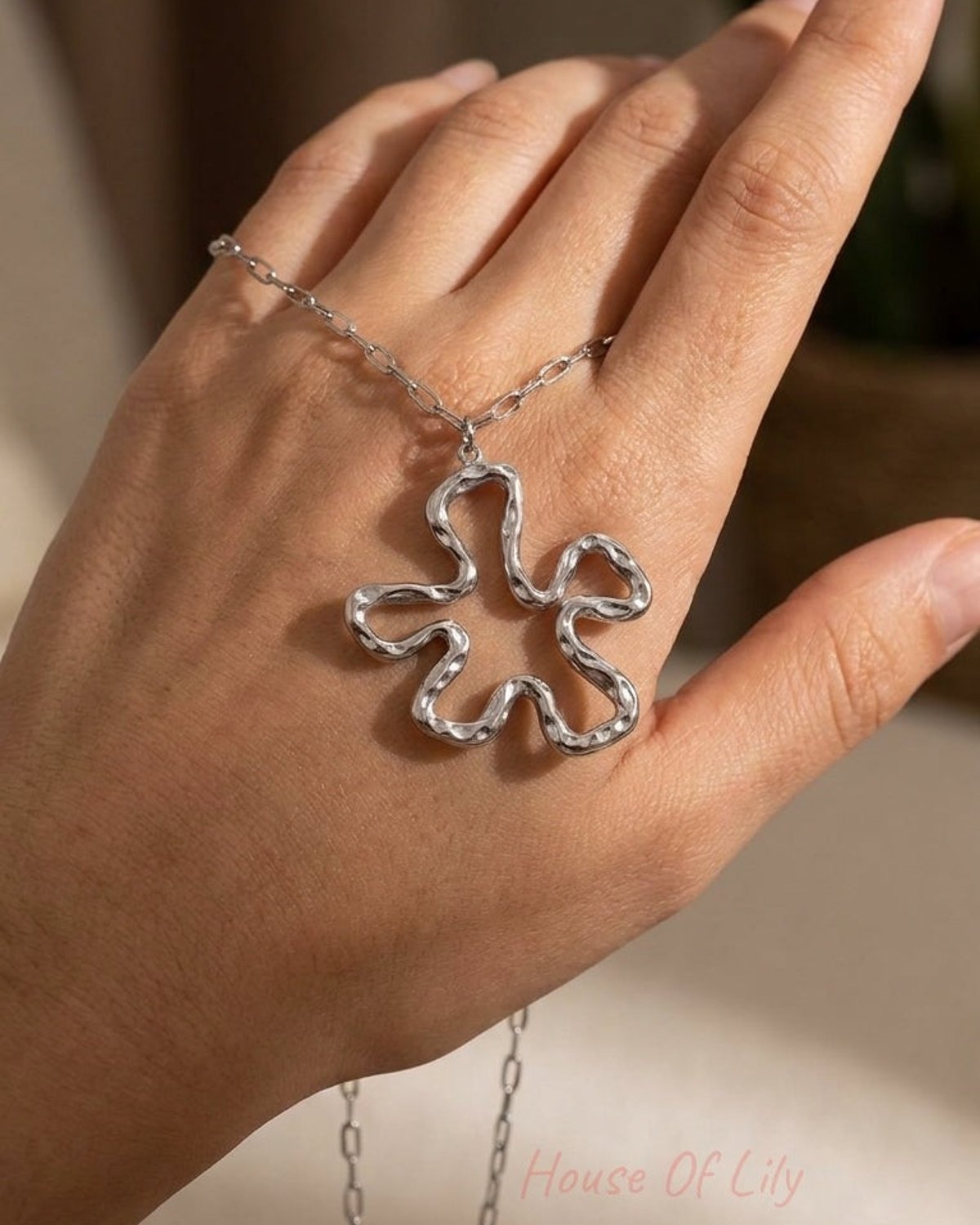 Iconic Lily Flower silver necklace featuring a textured, abstract flower pendant on a link chain.