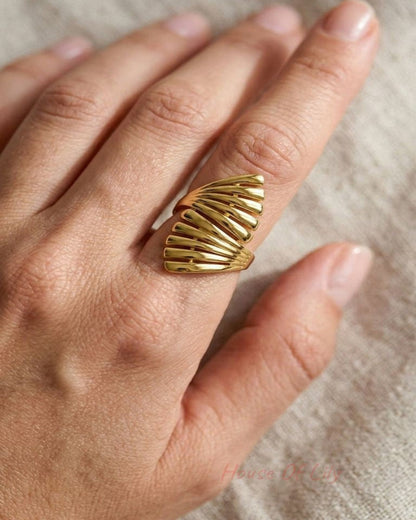 Close-up of the Sculpted Gold Statement ring on a slender finger, highlighting its organic wave pattern and high-shine gold finish in natural light.