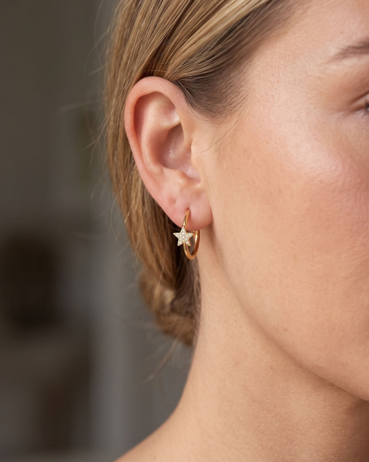 A pair of petite star-shaped rhinestone hoops with delicate bands resting on a dark matte grey slate surface.
