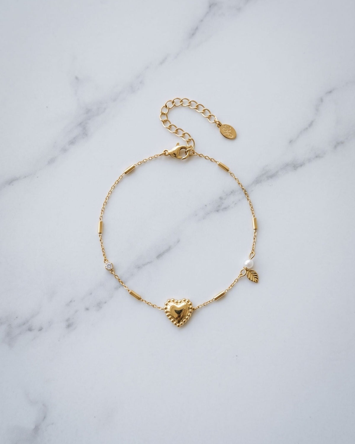 Elegant stainless steel heart charm bracelet displayed on a cool-toned marble surface.