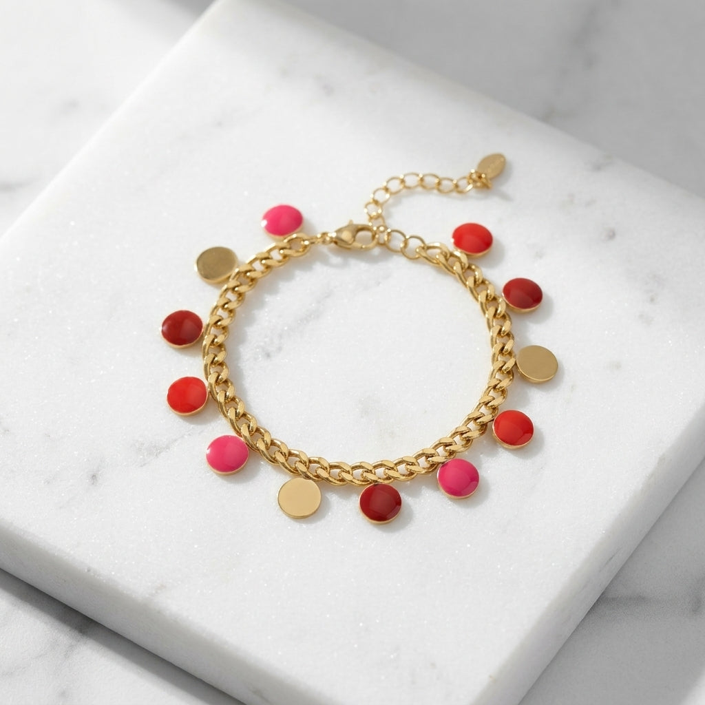 Red coin bracelet made of stainless steel with enamel charm, placed on a textured marble surface, showcasing its slim design and metallic finish.