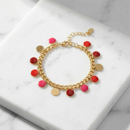 Red coin bracelet made of stainless steel with enamel charm, placed on a textured marble surface, showcasing its slim design and metallic finish.