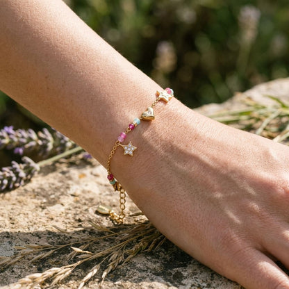 Close-up of Starry Heart Magic charm bracelet on wrist, featuring star and heart shapes with rhinestones, reflecting sunlight and showcasing its delicate design.