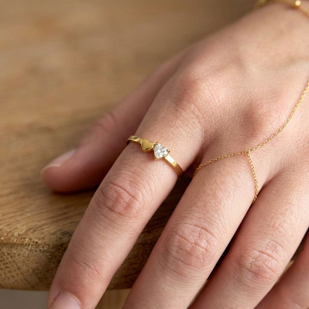 Small sparkling heart detail ring made of stainless steel with rhinestones, placed on a wooden surface with warm natural lighting.