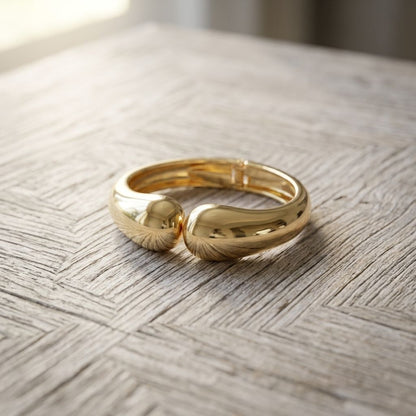 Close-up of the Wavy Twin Bangle resting on textured wooden surface, highlighting its irregular wavy shape and delicate shine.