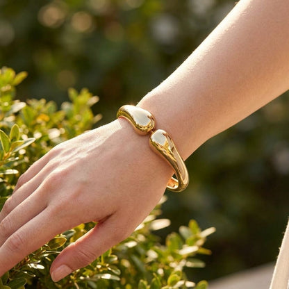 Wavy Twin Bangle worn on a model's wrist outdoors, showcasing its dainty design and irregular shape in warm daylight.
