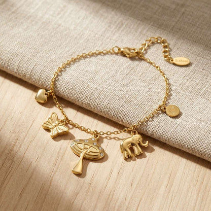 Close-up of the 'Wild Whispers' stainless steel charm bracelet with mushroom, elephant, butterfly, and heart charms, showcasing craftsmanship and rhinestone details.