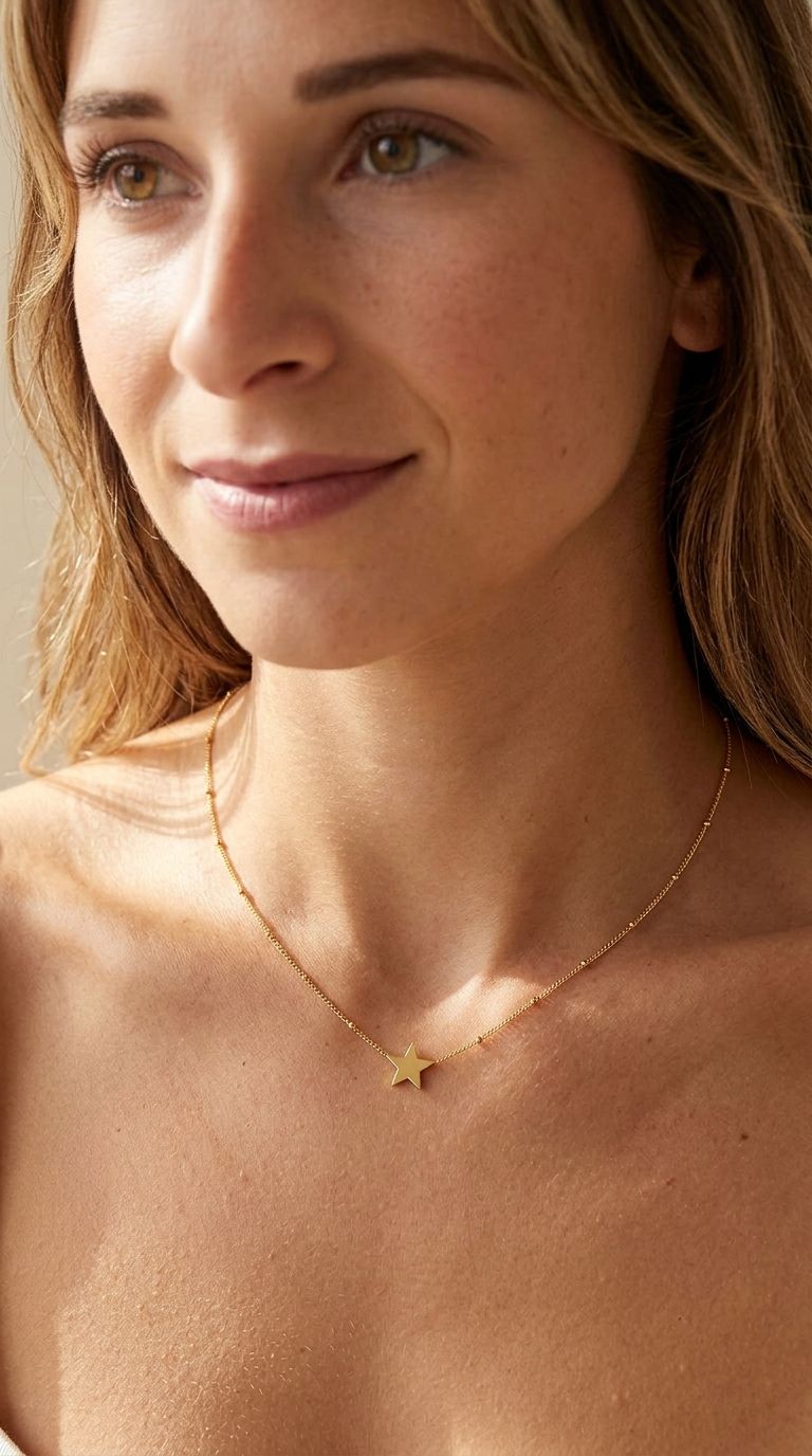 Woman wearing celestial star pendant necklace, emphasizing small size and subtle shine on collarbone with a blurred background.
