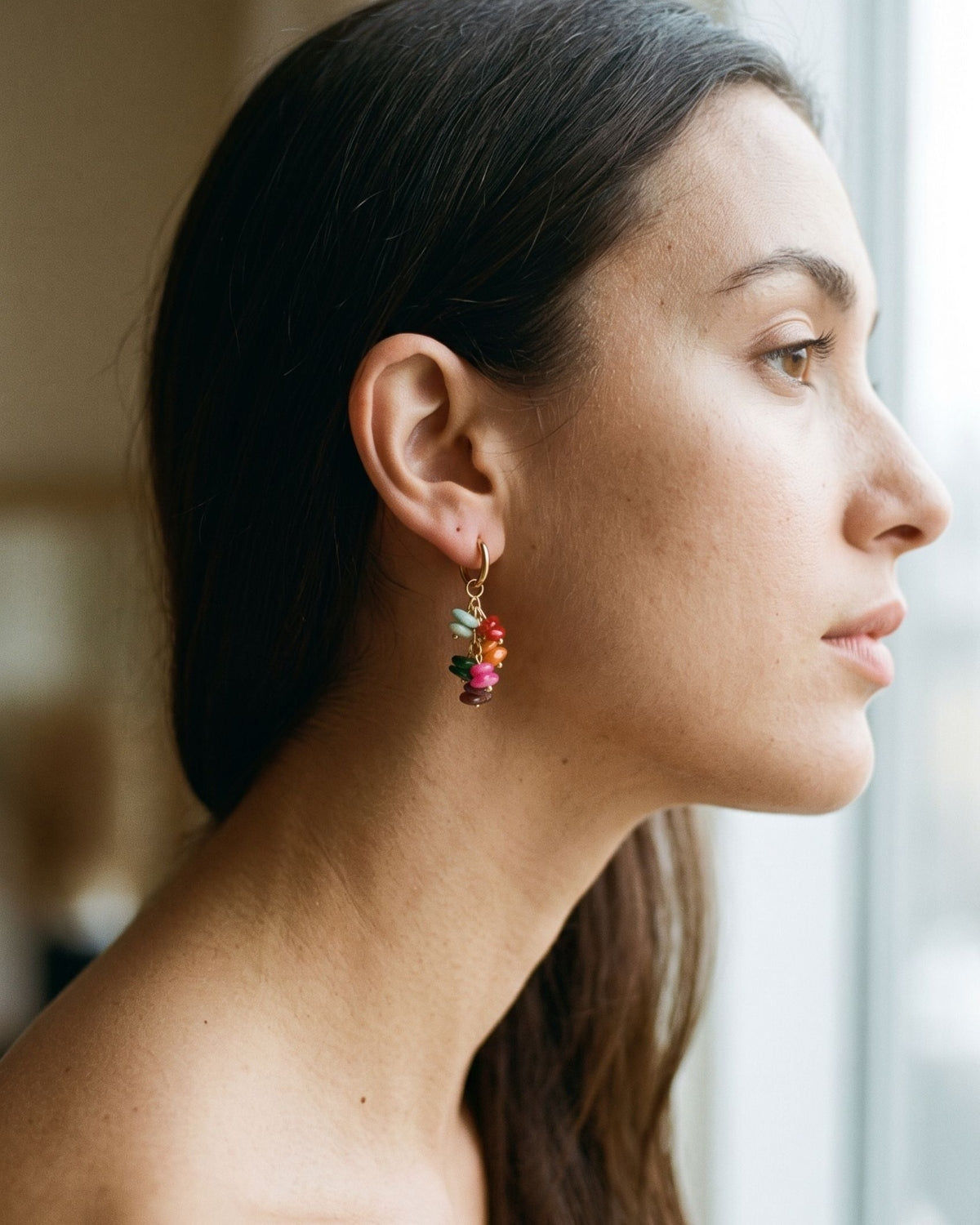 Close-up side profile of a woman wearing a delicate stone bead hoop earring.