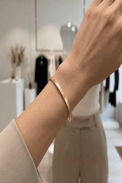 Stylish woman in a modern boutique wearing a slim gold bangle on her wrist, showcasing minimalist jewelry in a chic setting.